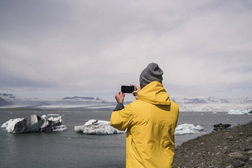 Älterer Mann, der den Vatnajokull-Gletscher mit einem Fernglas fotografiert, Island - UUF18710