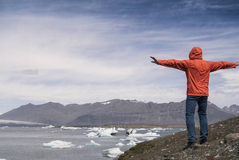 Älterer Mann mit Blick auf den Vatnajokull-Gletscher, Island, mit ausgestreckten Armen - UUF18717