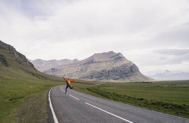 Mature man running and jumping on Ring Road 1 , Southern Region, Iceland - UUF18726