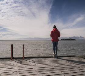 Young woman standig on a jetty, looking at the sea, South East Iceland - UUF18733