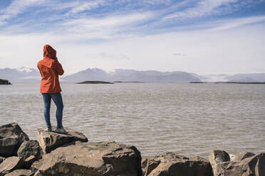 Young woman standig boulders, looking at the sea, South East Iceland - UUF18736