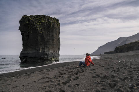 Frau am Lavastrand in Südostisland, Blick aufs Meer, lizenzfreies Stockfoto