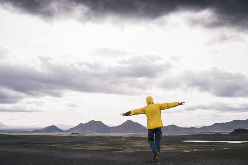 Mature man standing with arms out in the highland region of Iceland - UUF18746