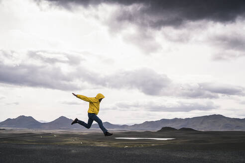 Mature man jumping for joy in the Highland Region, Iceland - UUF18747