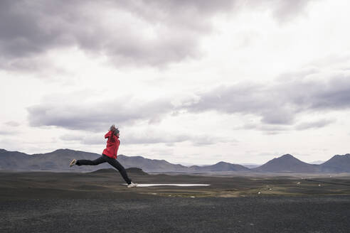 Älterer Mann, der vor Freude springt, in der Hochlandregion, Island - UUF18750