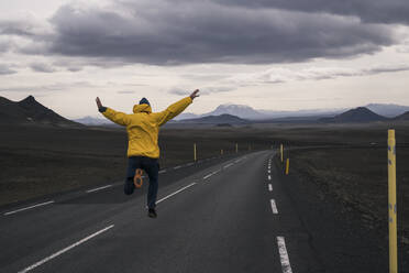 Happy man jumping for joy on an empty road, Iceland - UUF18752