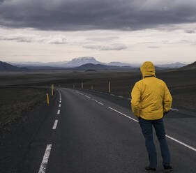 Man standing at empty road, looking at distance, Iceland - UUF18753