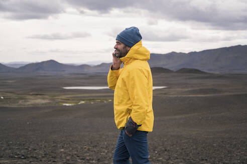 Älterer Mann, der im isländischen Hochland mit seinem Smartphone telefoniert - UUF18756