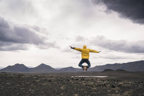 Mature man jumping for joy on a lava beach in Iceland - UUF18765