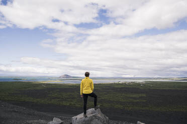 Junge Frau steht auf dem Hverfjall-Krater in der Nähe von Myvatn, Island, und betrachtet die Aussicht - UUF18784