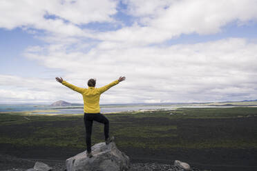 Junge Frau steht mit ausgebreiteten Armen auf dem Hverfjall-Krater in der Nähe von Myvatn, Island - UUF18785