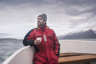 Älterer Mann schaut auf das Meer, Bootsfahrt auf dem Eyjafjordur Fjord, Island - UUF18802
