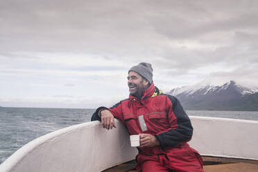 Mature man looking at the sea, boating on Eyjafjordur Fjord, Iceland - UUF18806