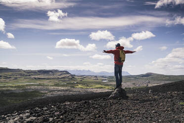 Wanderer in Vesturland, Island, stehend mit ausgestreckten Armen und Blick auf die Landschaft - UUF18814