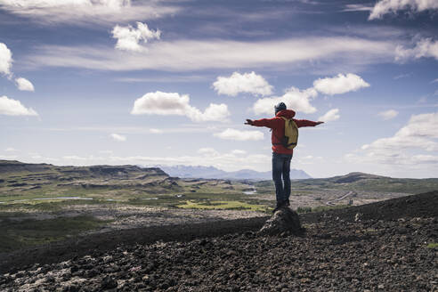 Wanderer in Vesturland, Island, stehend mit ausgestreckten Armen und Blick auf die Landschaft - UUF18814