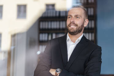 Lächelnder Geschäftsmann schaut aus dem Fenster - DIGF07906