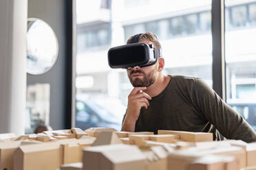 Mann mit Architekturmodell im Büro mit VR-Brille - DIGF07913