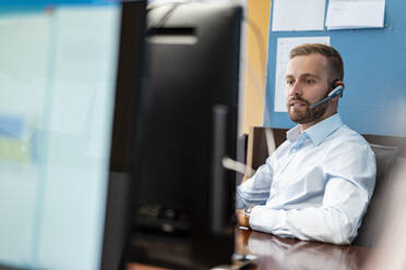 Businessman with headset at desk in office - DIGF07943