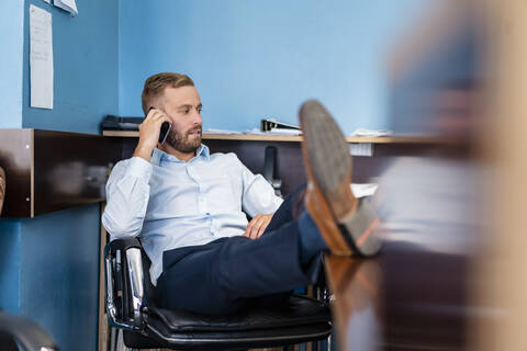 Geschäftsmann am Mobiltelefon im Büro, lizenzfreies Stockfoto