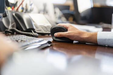 Nahaufnahme eines Geschäftsmannes, der eine ergonomische Maus im Büro benutzt - DIGF07952