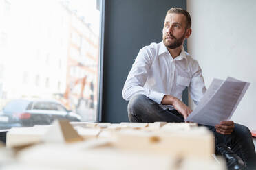 Geschäftsmann mit Papieren und Architekturmodell im Büro - DIGF07964