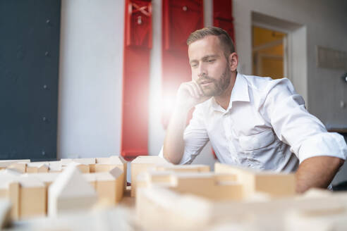 Geschäftsmann betrachtet Architekturmodell im Büro - DIGF07965