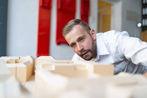 Geschäftsmann betrachtet Architekturmodell im Büro - DIGF07966