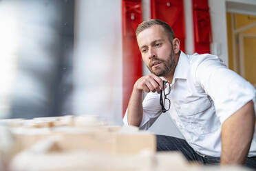 Businessman looking at architectural model in office - DIGF07967