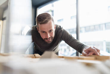 Mann betrachtet Architekturmodell im Büro - DIGF07978