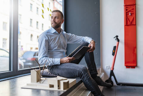 Businessman with tablet and architectural model in office stock photo