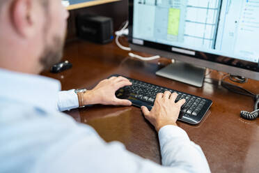 Nahaufnahme eines Geschäftsmannes bei der Arbeit an einem Desktop-PC im Büro - DIGF08002
