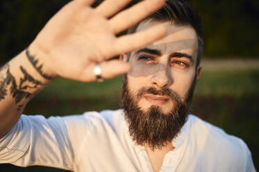 Porträt eines Mannes mit Bart, der seine Augen abschirmt - ZEDF02543