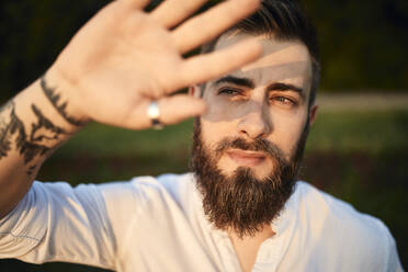 Portrait of a man with beard shielding his eyes - ZEDF02543