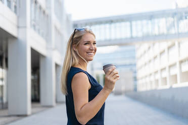 Porträt einer lächelnden blonden Geschäftsfrau mit Kaffee zum Mitnehmen im Sommer - DIGF08016