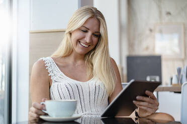 Porträt einer lächelnden blonden Frau in einem Café mit digitalem Tablet - DIGF08019