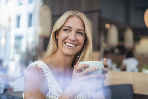 Porträt einer glücklichen blonden Frau beim Kaffeetrinken in einem Café - DIGF08021