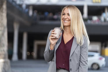 Portrait of happy blond businesswoman with coffee to go - DIGF08032