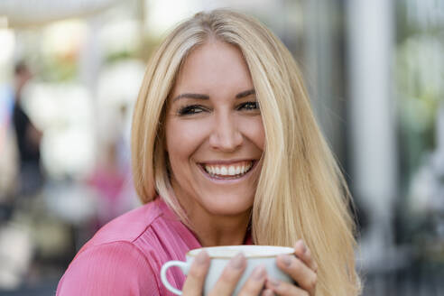 Porträt einer glücklichen blonden Frau mit einer Tasse Kaffee - DIGF08060