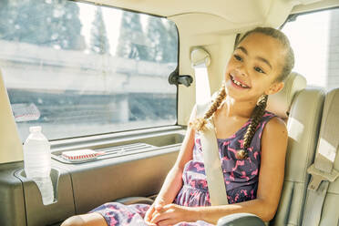 Mixed race girl smiling in back seat of car - BLEF14290