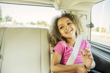 Mixed race girl smiling in back seat of car - BLEF14291