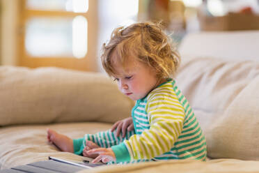 Caucasian baby boy using digital tablet on sofa - BLEF14309