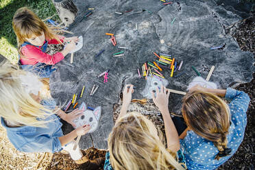 Caucasian children coloring on tree stump - BLEF14311