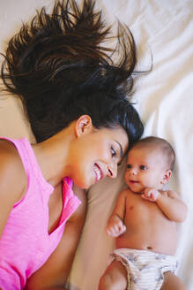 Glückliche Mutter auf dem Bett liegend mit einem kleinen Jungen - OCMF00577