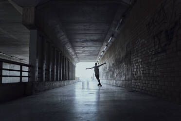 Silhouette eines jungen Mannes mit Longboard in einem Tunnel - AFVF03790