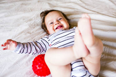 Kaukasisches Babymädchen lachend auf dem Bett - BLEF14340
