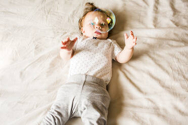 Caucasian baby girl playing with bubble on bed - BLEF14346