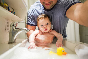 Nahaufnahme eines kaukasischen Vaters beim Baden eines kleinen Mädchens im Waschbecken - BLEF14347