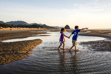 Weiße Kinder, die in Gezeitentümpeln am Strand spazieren gehen, Cannon Beach, Oregon, Vereinigte Staaten - BLEF14351