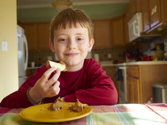 Kaukasischer Junge isst Apfel mit Erdnussbutter als Snack - BLEF14378