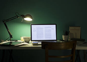 Computer und Mobiltelefon werden nachts von der Schreibtischlampe beleuchtet - BLEF14419
